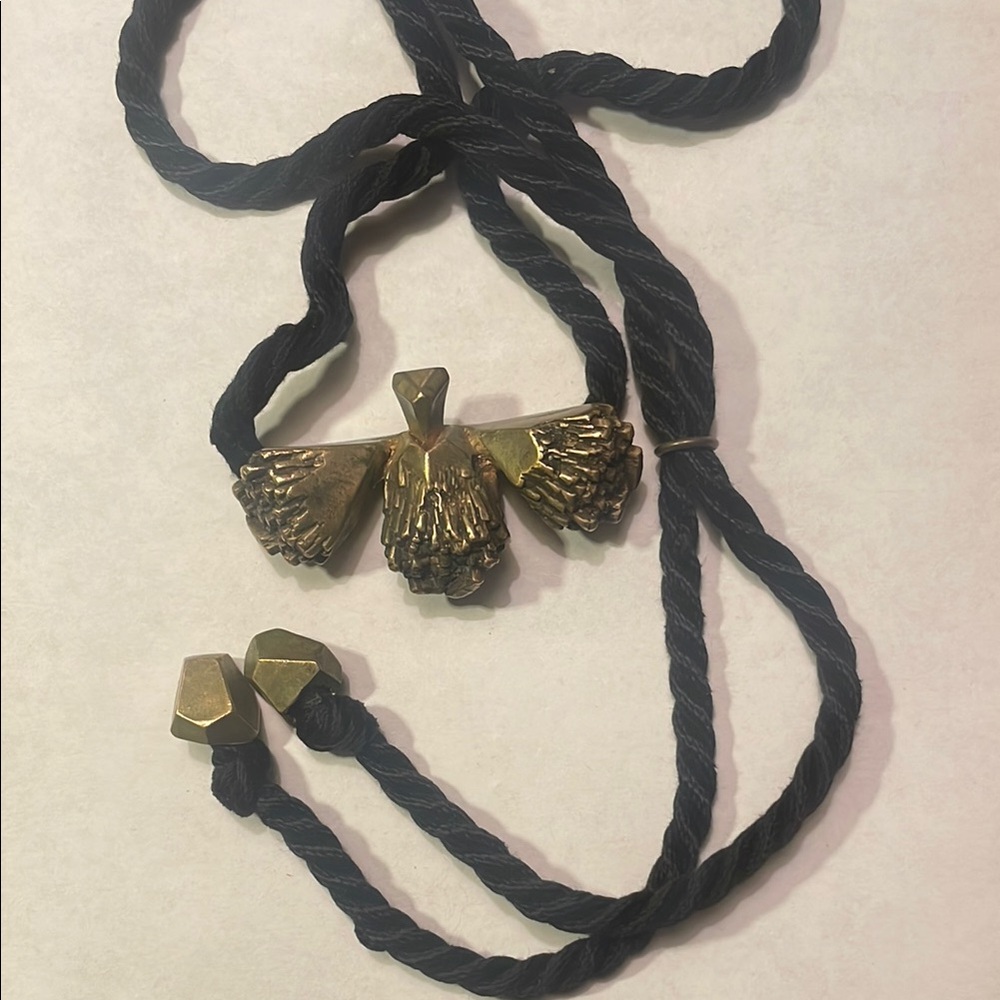 Abstract brass eagle pendant on black rope necklace